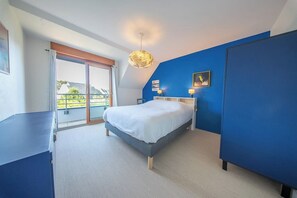 Ein Schlafzimmer mit Bett, Kleiderschrank, Schreibtisch, Balkon und Deckenleuchte.