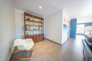 Un salon avec un fauteuil à bascule blanc, un meuble en bois doté de portes en verre et un canapé en cuir noir.