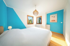 Une chambre à coucher comprenant un lit, une commode, une table de chevet, une lampe et un luminaire au plafond.