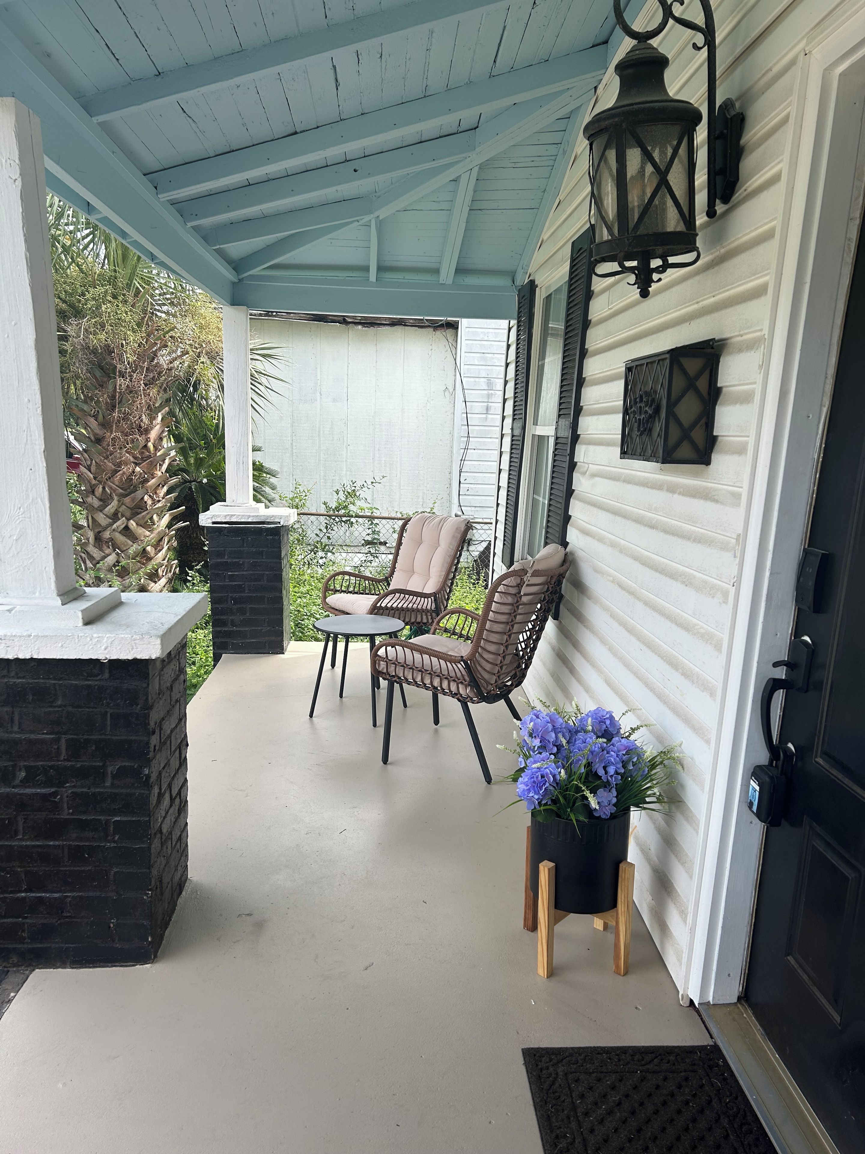 Une véranda abritée avec deux fauteuils en osier, une petite table et une plante en pot.