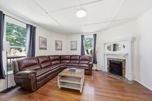 A living room with a brown leather sectional sofa, a wooden coffee table, a fireplace, and framed artwork on the walls.