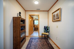 A hallway with a wooden cabinet, a bench, a rug, and a painting on the wall. - The Chateaugay Lake Mansion (Lyon Mountain)