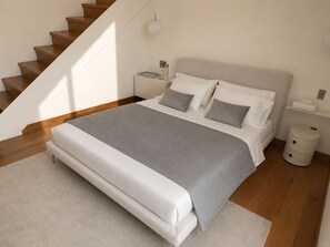 Ein Schlafzimmer mit einem Bett, einem Nachttisch, einer Nachttischlampe und einem Mülleimer.