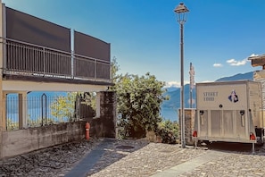 A building with a balcony, a street lamp, and a sign for street food. - Sunset View lago Maggiore (Maccagno Con Pino E Veddasca)