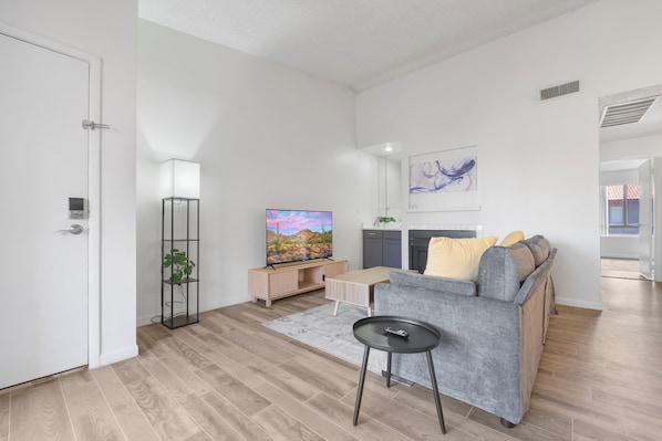Een moderne woonkamer met een bank, televisie en een klein tafeltje.