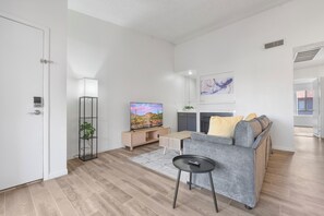 A modern living room with a sofa, TV, and a small table.