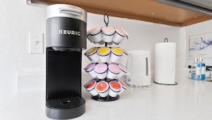 Máquina de café Keurig com suporte para caneca e um dispensador de toalhas de papel brancas em uma bancada de cozinha.