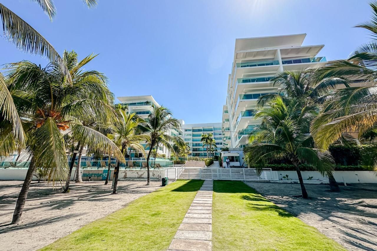 A modern hotel with a central staircase, palm trees, and a clear sky.