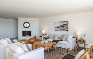 A modern living room with a fireplace, a round mirror, a coffee table, and a sofa set.