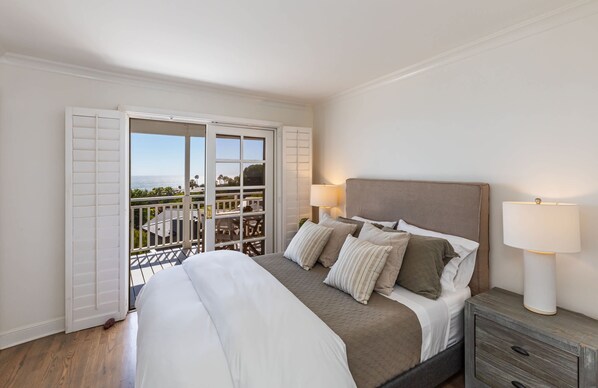 A bedroom with a bed, bedside lamps, and a view of the outdoors through a sliding door.