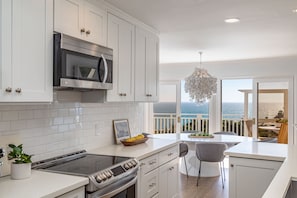 A modern kitchen with white cabinetry, a built-in microwave, and a stove.
