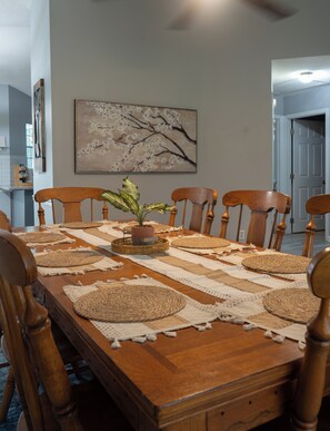 Una mesa de comedor con manteles individuales, sillas y una decoración central.