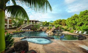 Piscina de resort con jacuzzi, sillas de descanso y una cascada.
