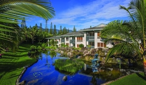 Un hotel con piscina, exuberante vegetación y un cielo azul despejado.