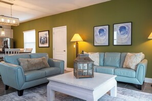 Ein Wohnzimmer mit zwei Sofas, einem Couchtisch, einer Lampe und Kunstwerken an der Wand.