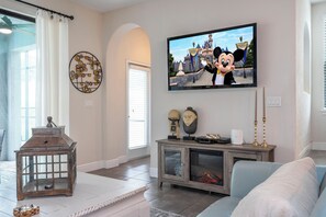 Ein Wohnzimmer mit Flachbildfernseher an der Wand, einem Holztisch, einem Kamin und einer Couch.