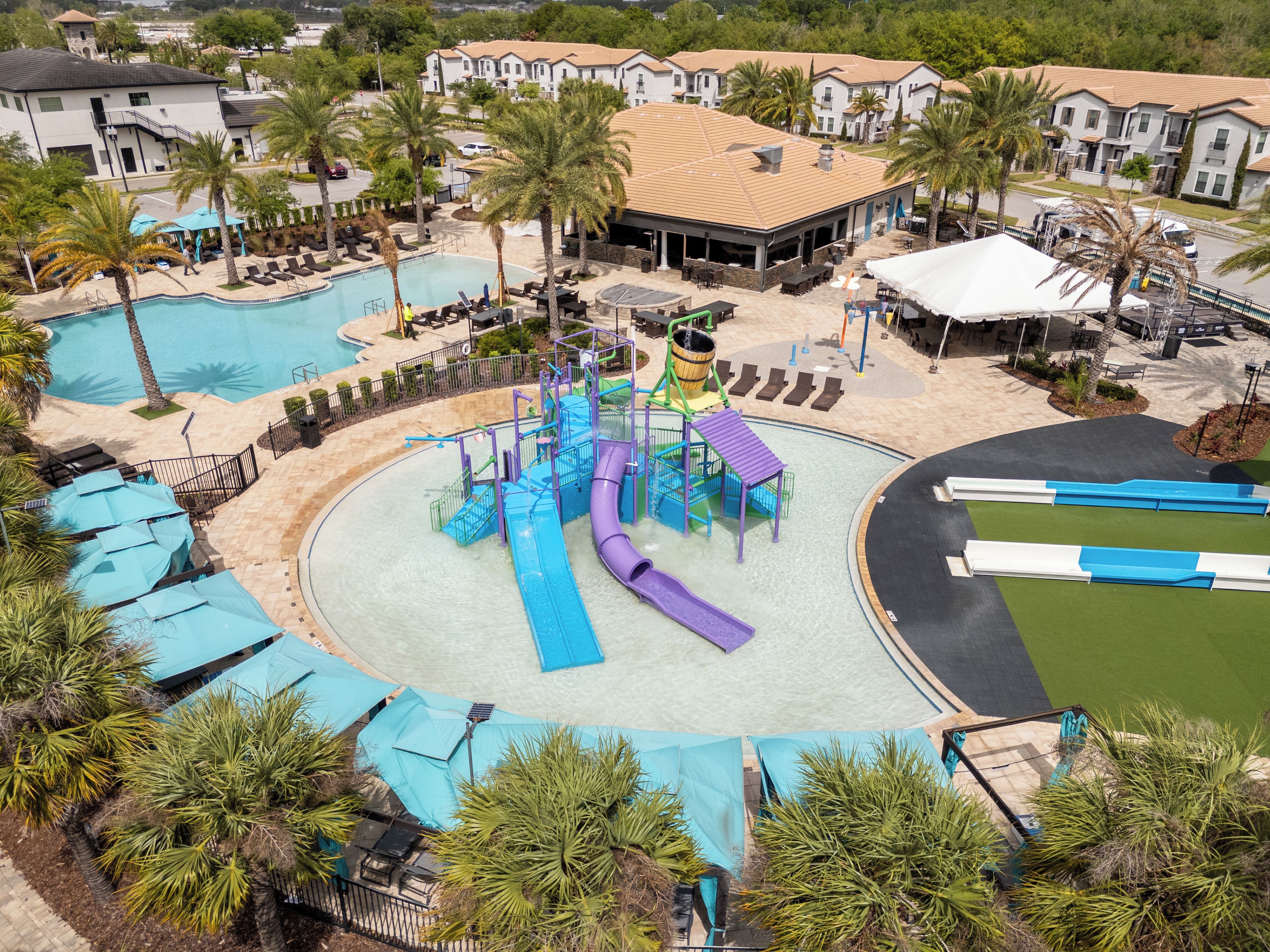 A water park with multiple slides and pools, surrounded by palm trees and lounge areas.