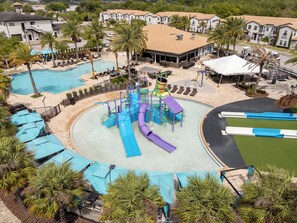 Een waterpark met meerdere glijbanen en zwembaden, omringd door palmbomen en terrasjes.