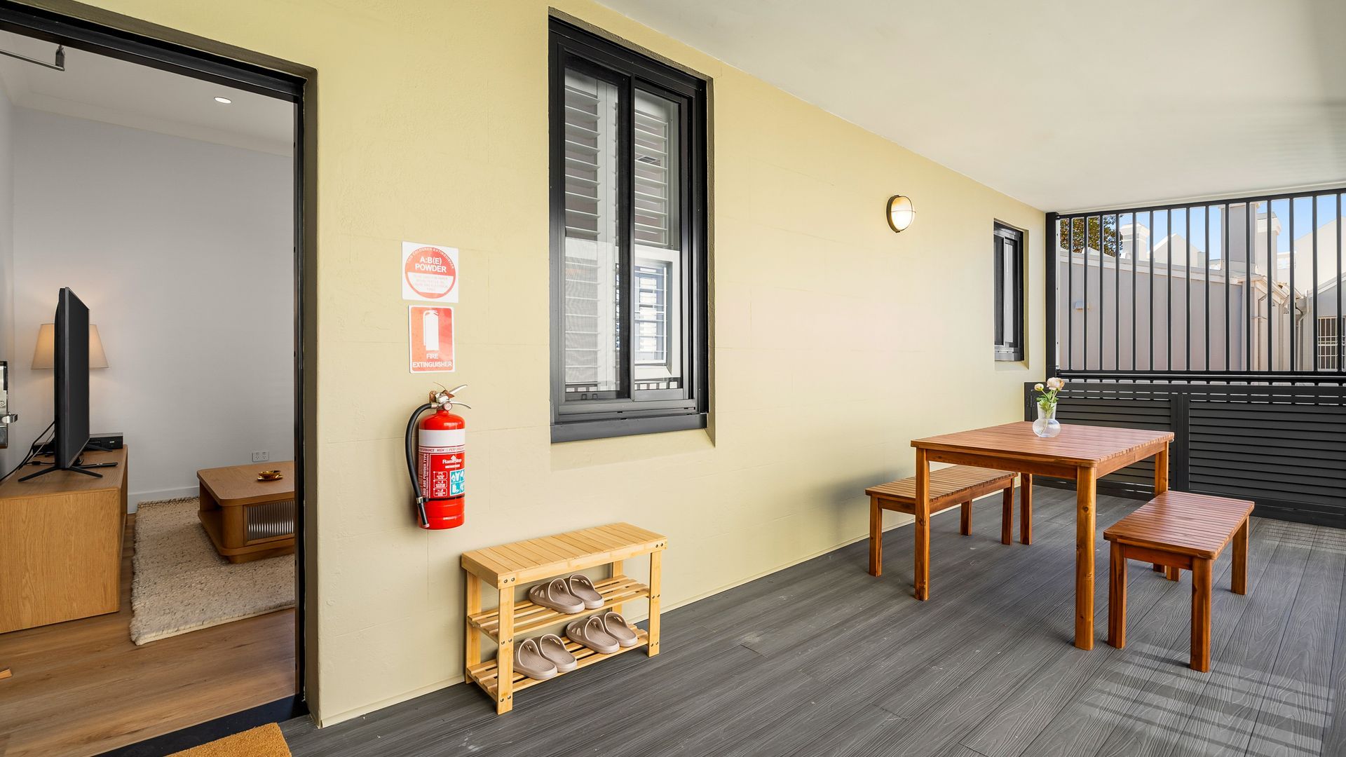 Ein Zimmer mit einem Holztisch, Stühlen, einem Feuerlöscher und einem Fernseher auf einem Beistelltisch.