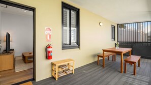 Ein Zimmer mit einem Holztisch, Stühlen, einem Feuerlöscher und einem Fernseher auf einem Beistelltisch.