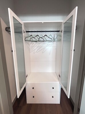 A walk-in closet with a hanging rod and three drawers.
