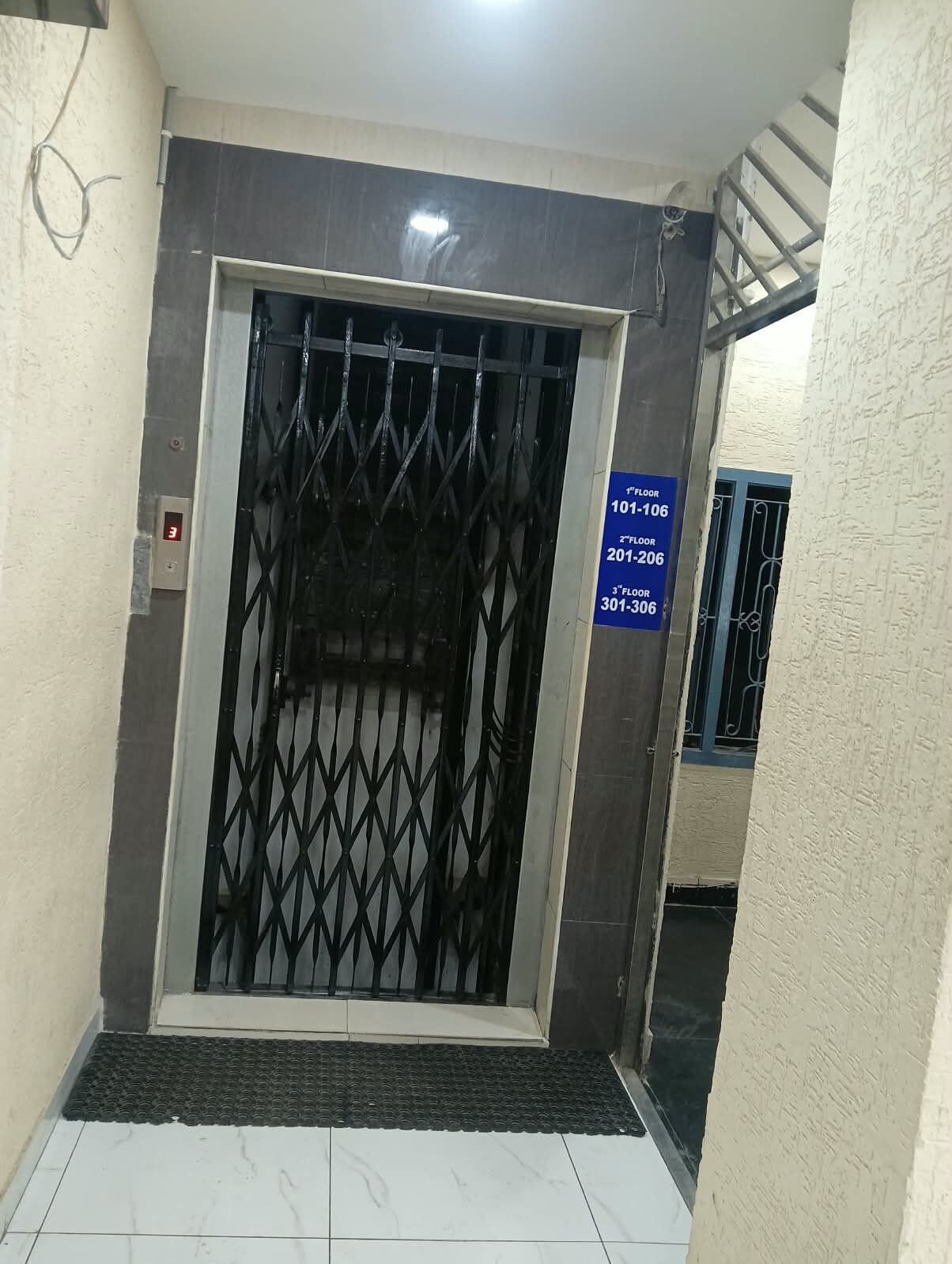 An elevator with a metal gate, a digital floor indicator, and a sign indicating floor numbers.