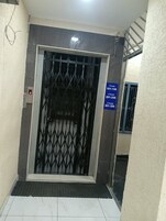 An elevator with a metal gate, a digital floor indicator, and a sign indicating floor numbers.