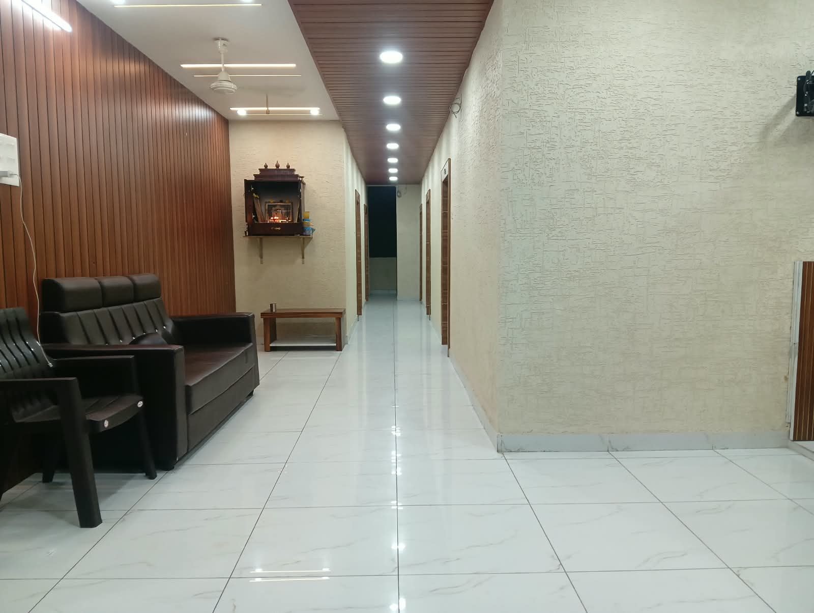 Un vestíbulo de hotel con una recepción, zona de estar y un pasillo que conduce a otras habitaciones.