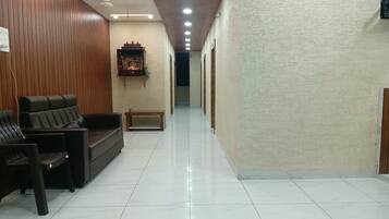 Un vestíbulo de hotel con una recepción, zona de estar y un pasillo que conduce a otras habitaciones.