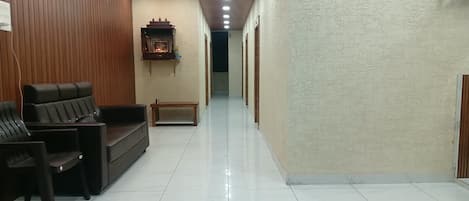 A hotel lobby with a reception desk, seating area, and a hallway leading to other rooms.