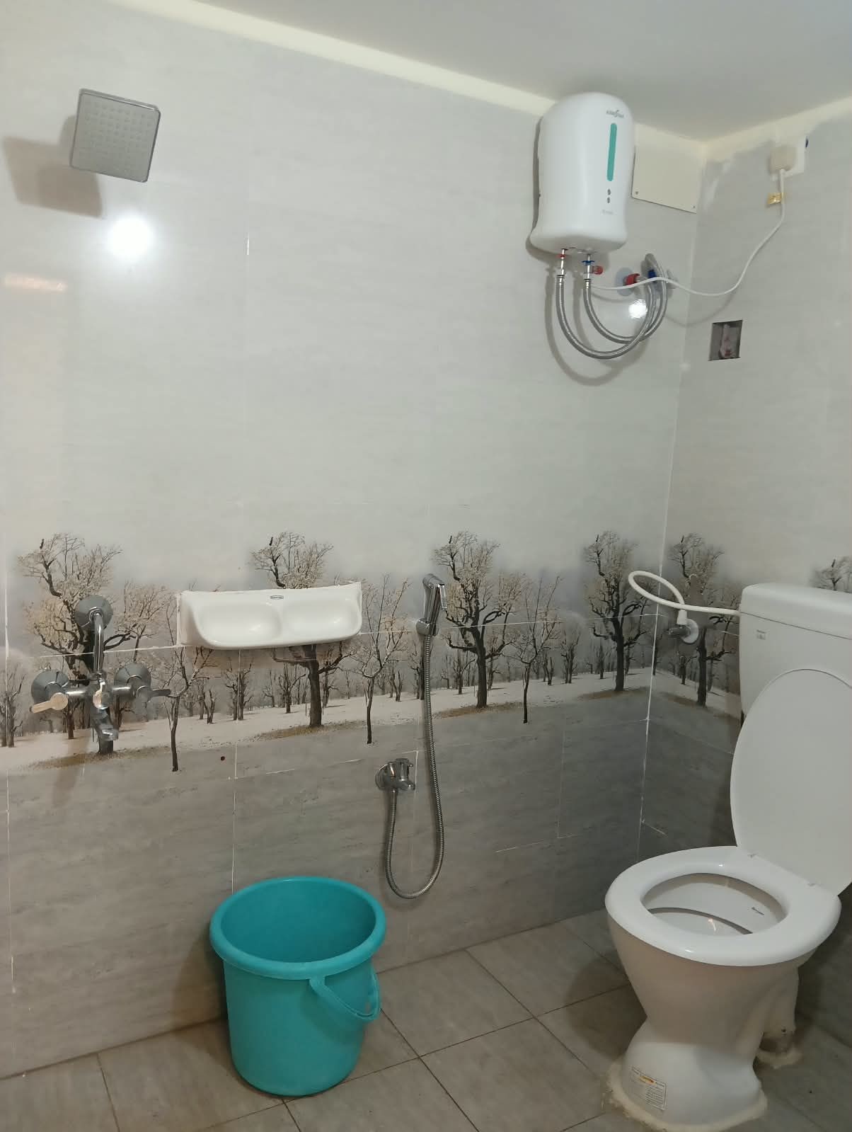 Un baño con inodoro, lavabo, ducha y un balde.