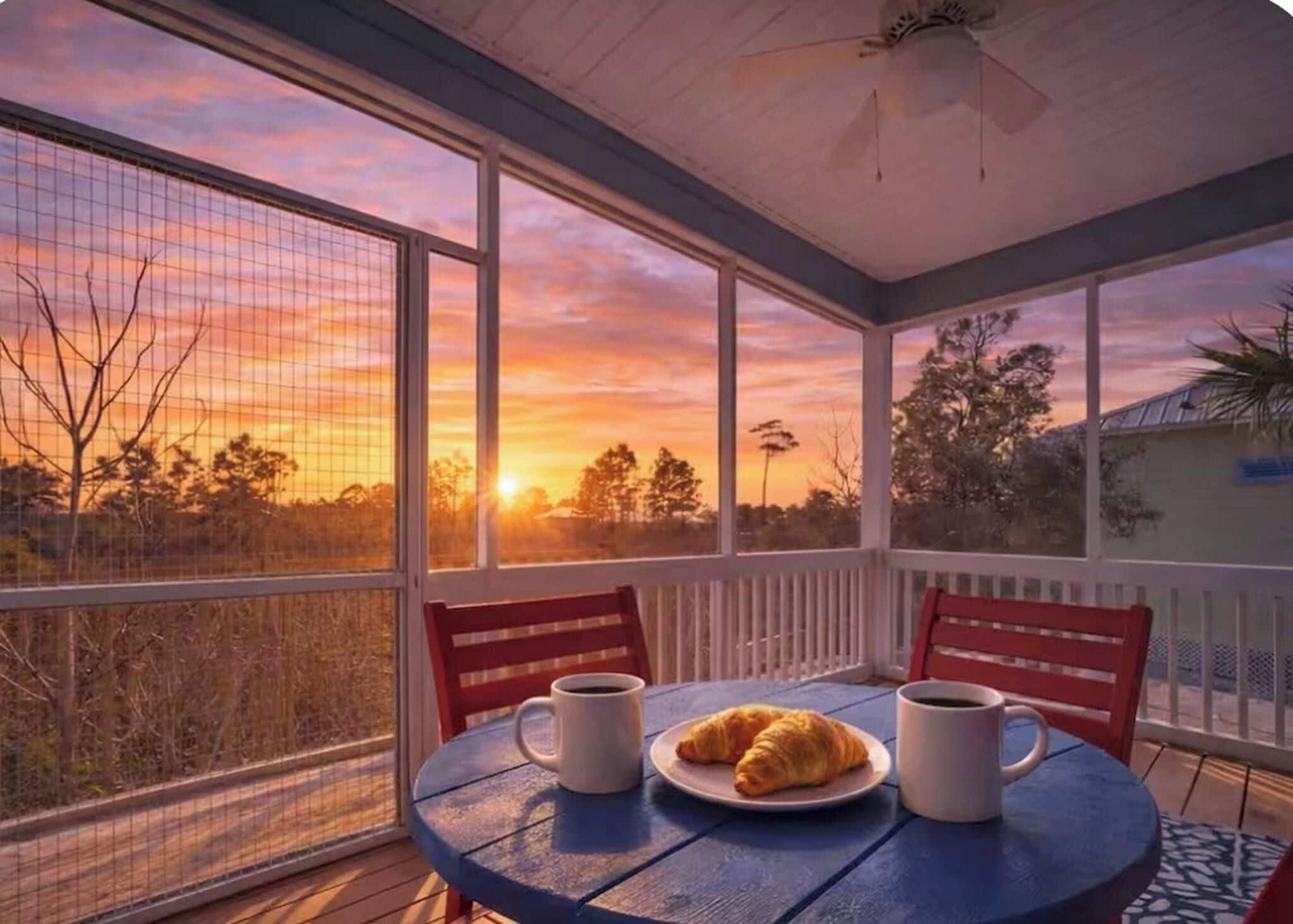 Un patio techado con una mesa dispuesta para el desayuno, con vista a una puesta de sol.