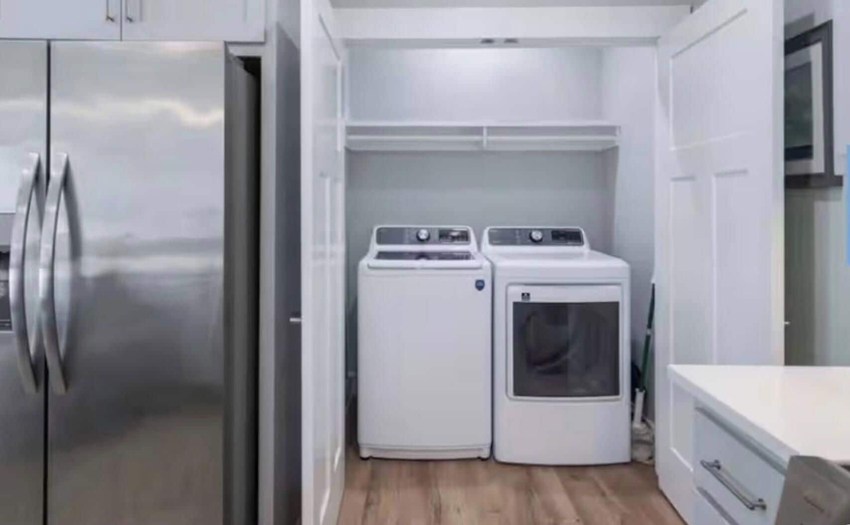Een kleine keuken met een roestvrijstalen koelkast, een wasmachine en een droger.