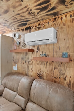 A room with a wooden ceiling, a mounted air conditioner, and a leather sofa. - HOPEWELL OASIS - TAMPA / Your Private Wellness Retreat with Hot Tub & Sauna (Tampa)