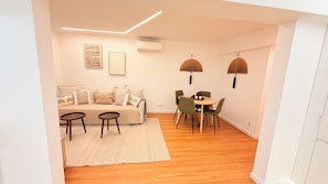 A modern living space with a sofa, two small tables, a dining table with chairs, and decorative fans. - Modern 1 bedroom apartment in the heart Cascais with AC, amenities (Cascais)