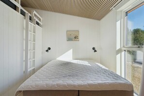 Ein Schlafzimmer mit einem Bett, einer Leiter, einem Bild an der Wand und einem Fenster.