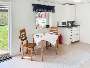 A compact kitchen with a dining table, chairs, a microwave, and a coffee maker. - Newly renovated (2025) and very fresh cottage (Figeholm)