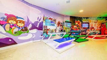 A children's play area with colorful murals, gaming stations, and seating.