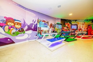 A children's play area with colorful murals, gaming stations, and seating.