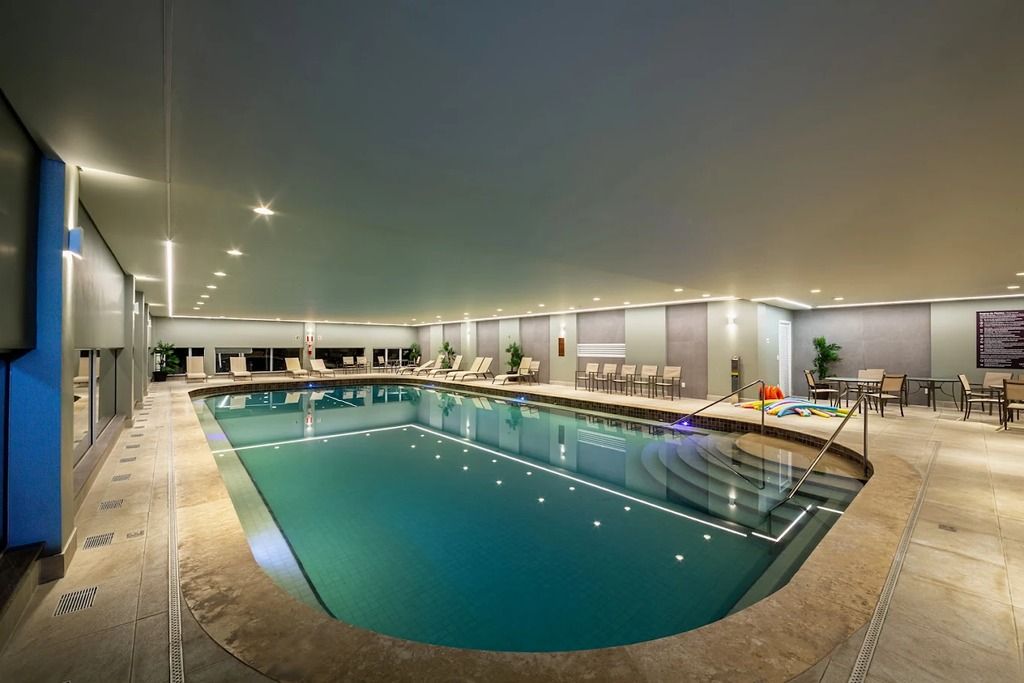 Una piscina interior con diseño curvo, rodeada de sillones de descanso y una zona de estar.