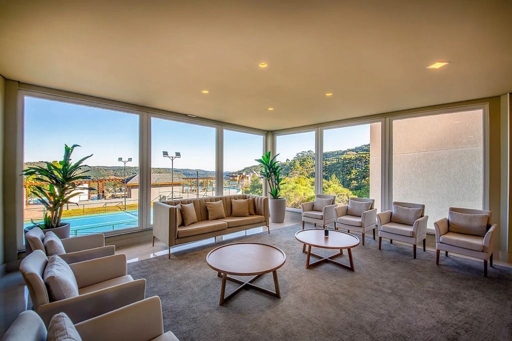 A spacious room with a large window, a sofa, armchairs, and a coffee table.