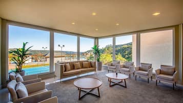 A spacious room with a large window, a sofa, armchairs, and a coffee table.