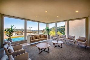 A spacious room with a large window, a sofa, armchairs, and a coffee table.