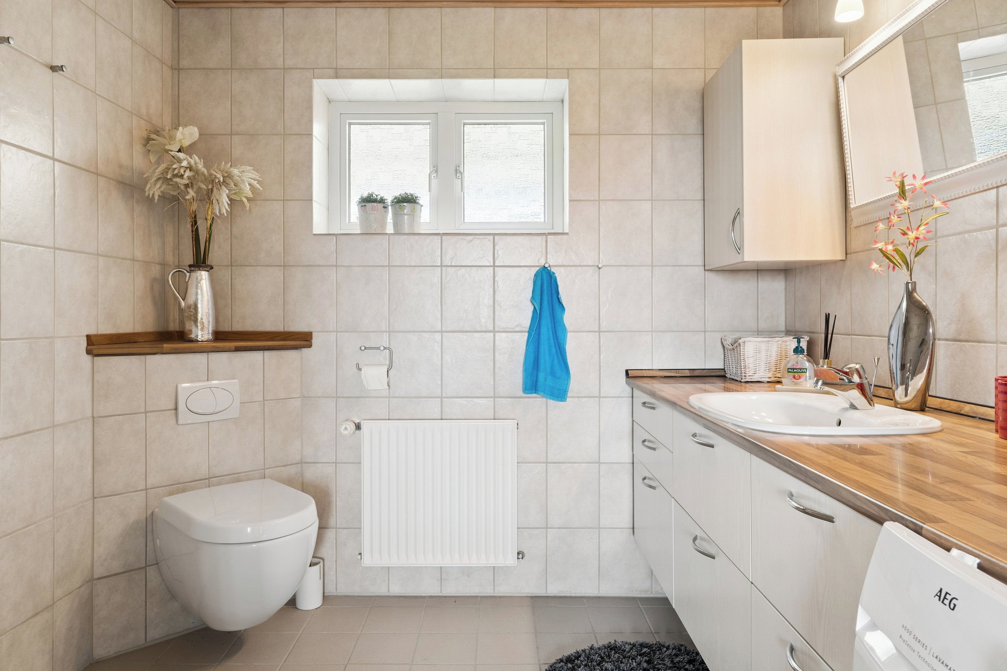 Een moderne badkamer met toilet, wastafel, spiegel en raam.
