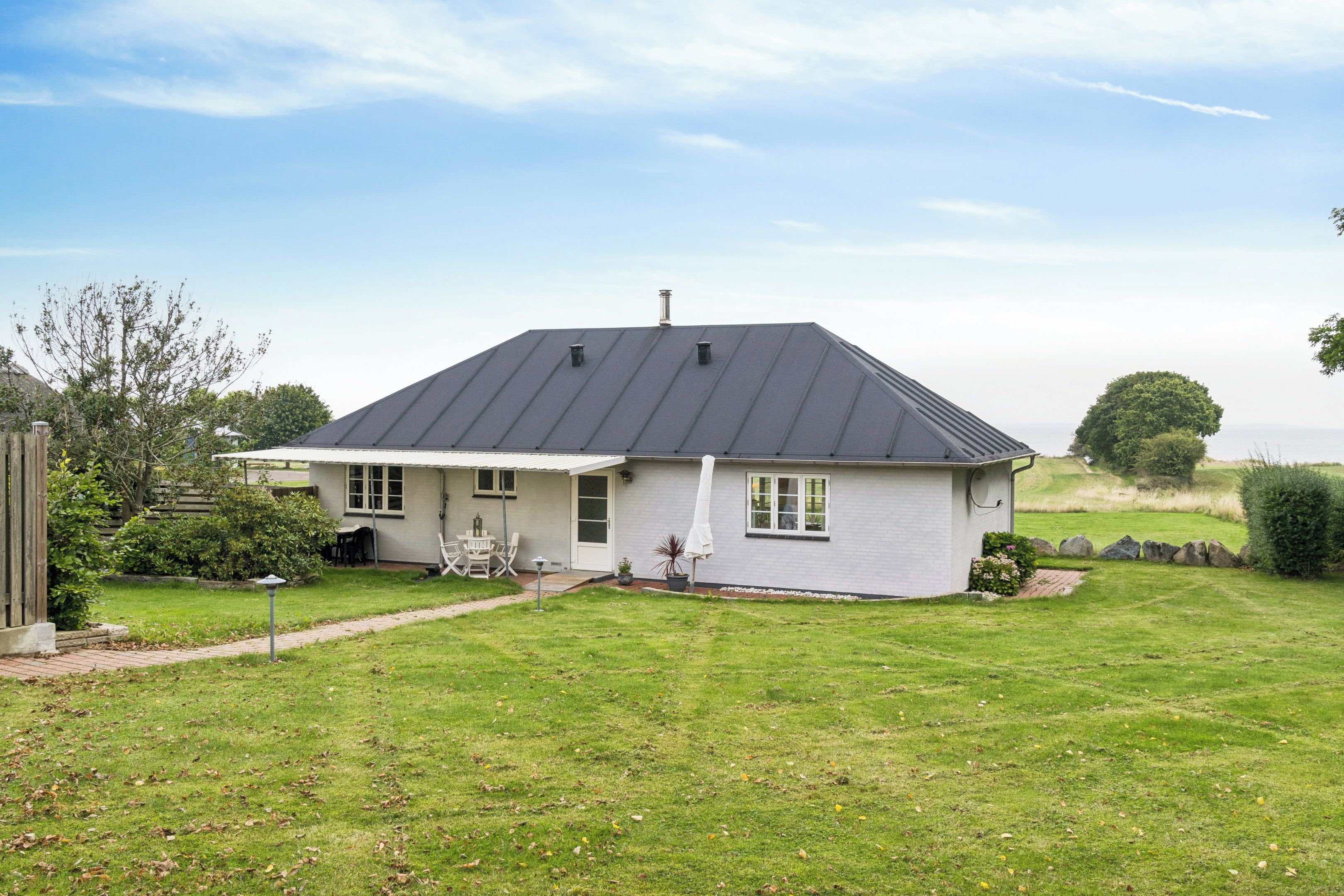 A single-story house with a sloped roof, a front porch, and a small garden area.