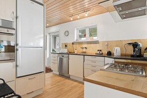 A modern kitchen with stainless steel appliances, wooden cabinets, and a gas stove. - Holiday home near the water on beautiful Als (Augustenborg)