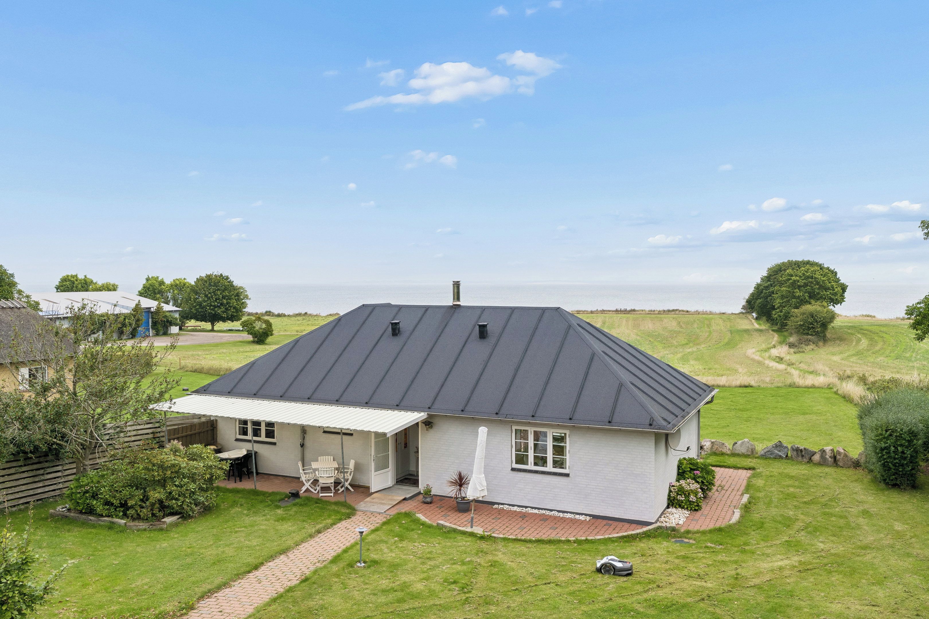 A single-story house with a sloped roof, a covered patio, and a well-maintained lawn.