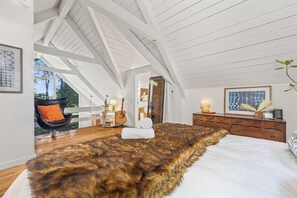Ein Schlafzimmer mit einem großen Bett, einer Holzkommode, einer Gitarre und einem Spiegel.
