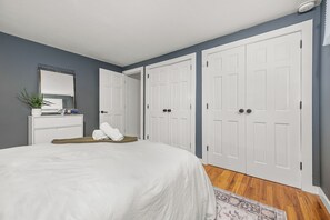 A bedroom with a bed, a dresser, a mirror, and two white doors. - Modern A-frame cabin retreat in the woods of Middletown (Middletown)