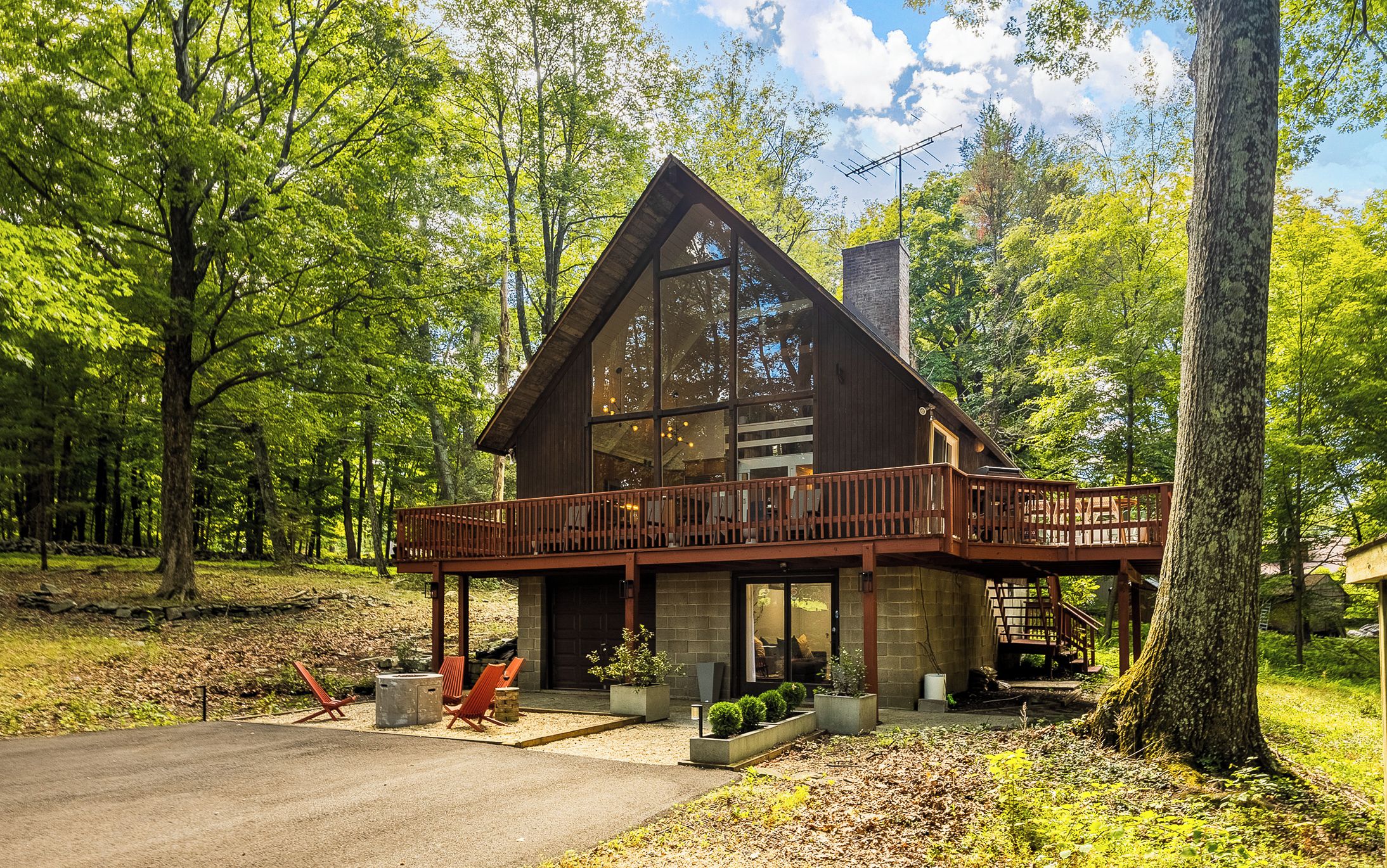 A cabin with a deck, surrounded by trees.
